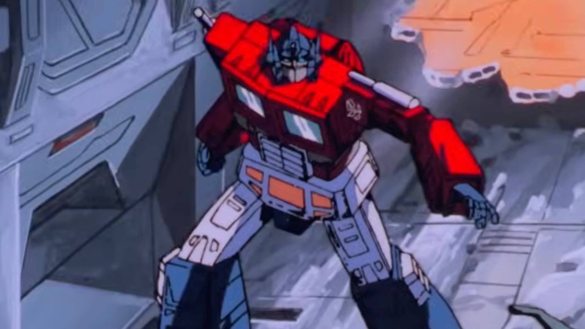 A vintage 1980s cel-shaded animation still from The Transformers: The Movie showing Optimus Prime standing battle-ready in a ruined, angular industrial corridor amid debris and a glowing breach.